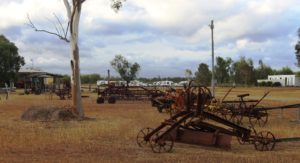 Old farm machinery with visiting caravans in the background